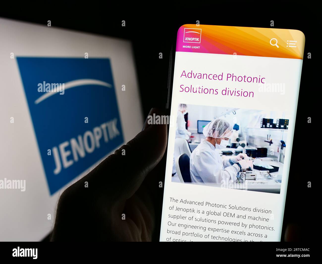 Personne tenant le téléphone portable avec la page Web de la société allemande de photonique Jenoptik AG sur l'écran devant le logo. Concentrez-vous sur le centre de l'écran du téléphone. Banque D'Images