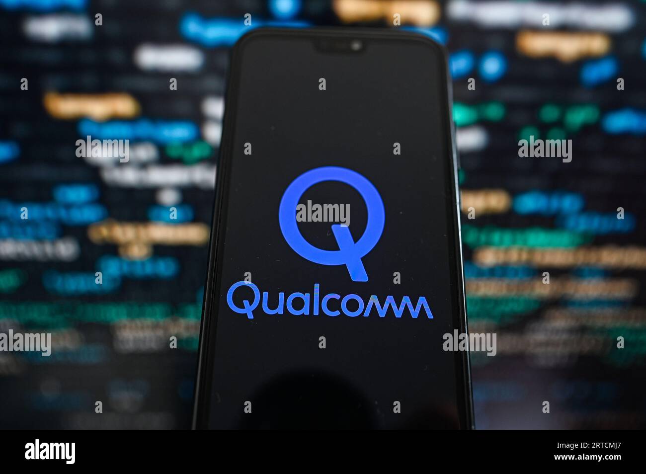Sur cette photo, un logo Qualcomm affiché sur un smartphone avec un code de programmation sur le fond. Banque D'Images