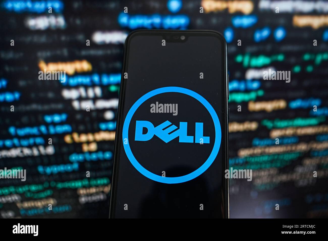 Sur cette photo, un logo Dell s'affiche sur un smartphone avec un code de programmation à l'arrière-plan. Banque D'Images