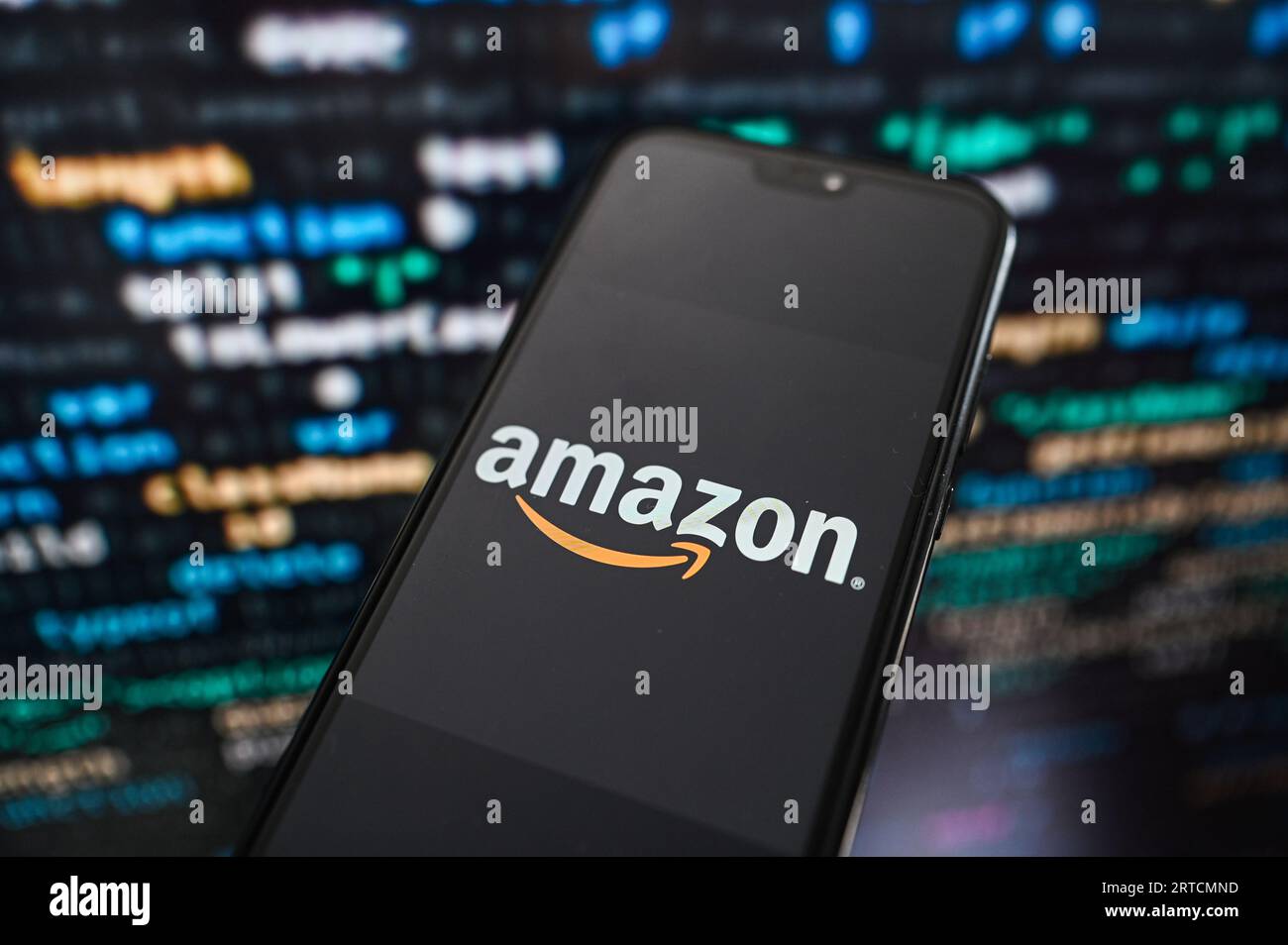 Dans cette illustration photo, un logo Amazon affiché sur un smartphone avec un code de programmation en arrière-plan. Banque D'Images