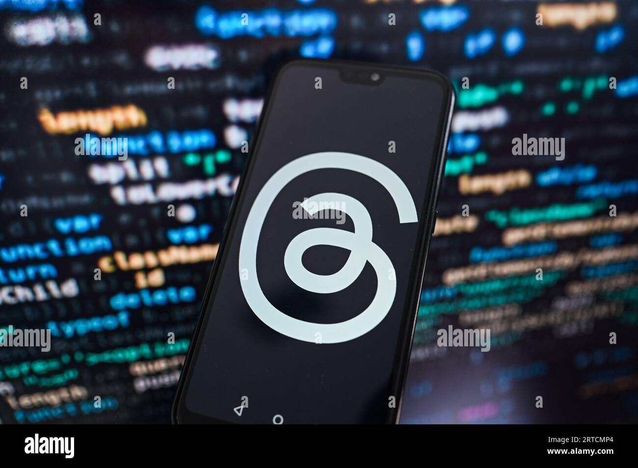 Dans cette illustration photo, un logo de threads affiché sur un smartphone avec code de programmation en arrière-plan. Banque D'Images
