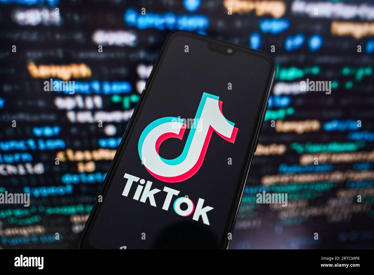 Sur cette photo, un logo TikTok affiché sur un smartphone avec un code de programmation en arrière-plan. Banque D'Images