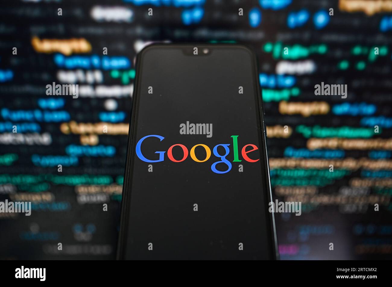 Sur cette photo, un logo Google affiché sur un smartphone avec un code de programmation en arrière-plan. Banque D'Images
