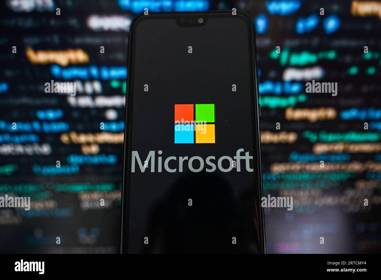 Sur cette photo, un logo Microsoft s'affiche sur un smartphone avec un code de programmation en arrière-plan. Banque D'Images