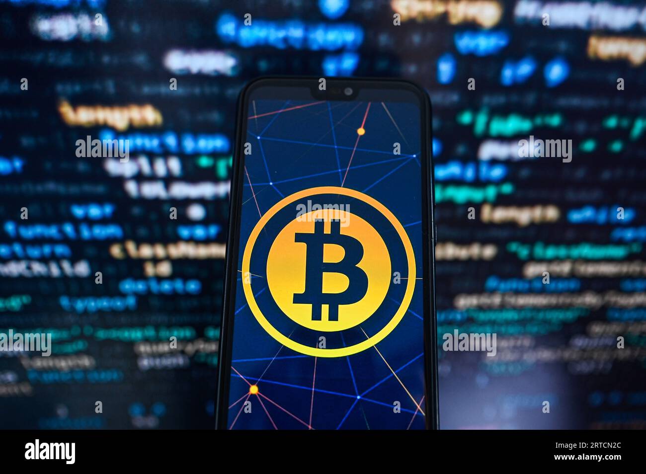 Dans cette illustration photo, un logo Bitcoin affiché sur un smartphone avec un code de programmation sur le fond. Banque D'Images