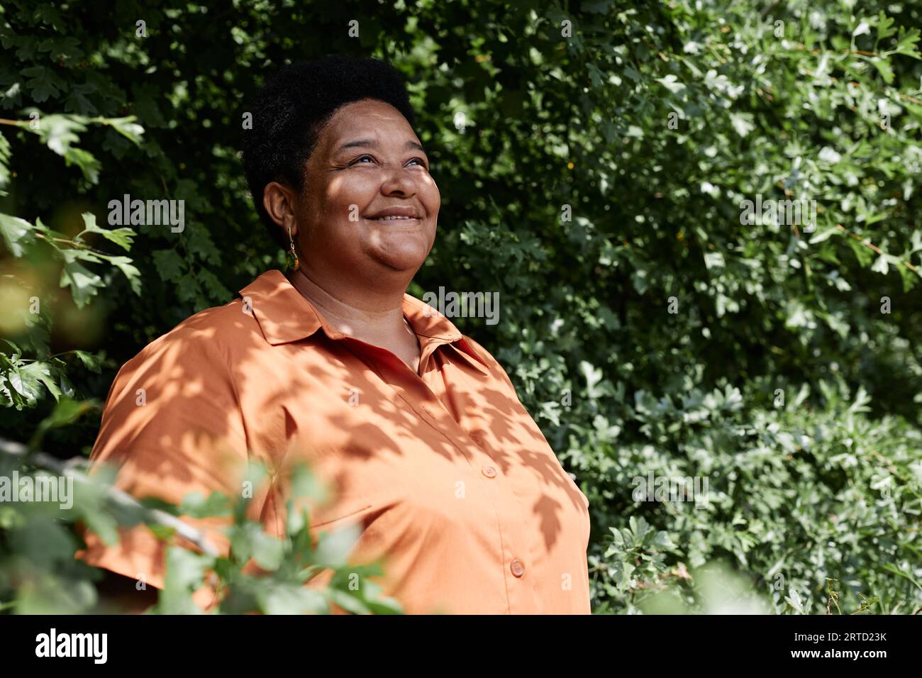 Portrait de femme noire senior regardant loin contre la verdure à l'extérieur, espace de copie Banque D'Images