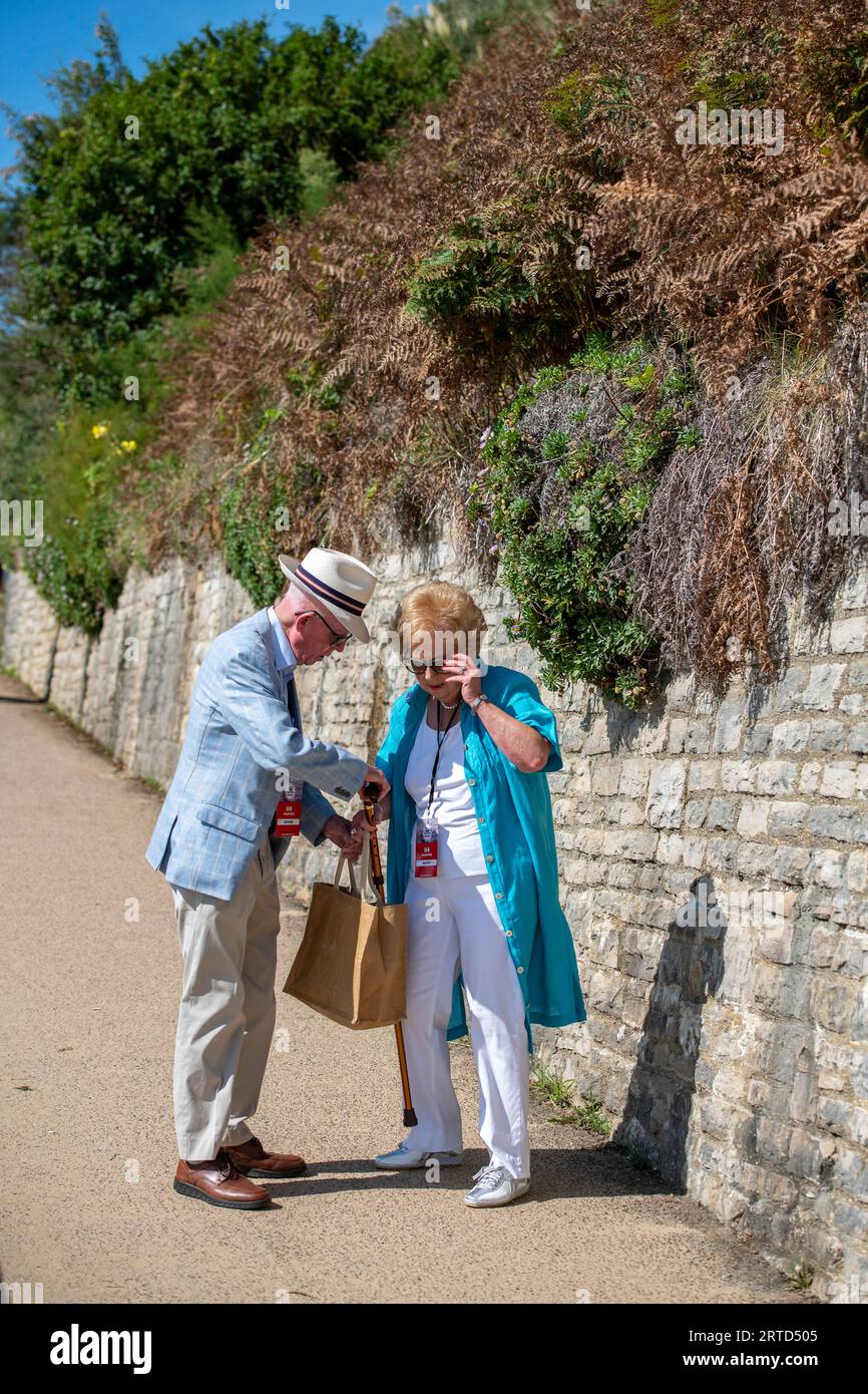 couple âgé habillé intelligemment regardant dans un sac et parlant alors qu'il est dehors pour une promenade ensemble sur une journée ensoleillée. Banque D'Images