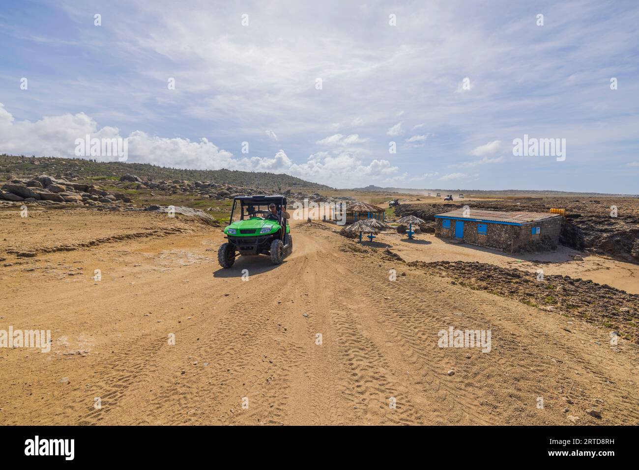 Touristes sur les voitures hors route passant par la maison abandonnée sur la route du désert rocheux d'Aruba. Banque D'Images Touristes sur les voitures hors route passant par la maison abandonnée sur la route du désert rocheux d'Aruba. Banque D'Images