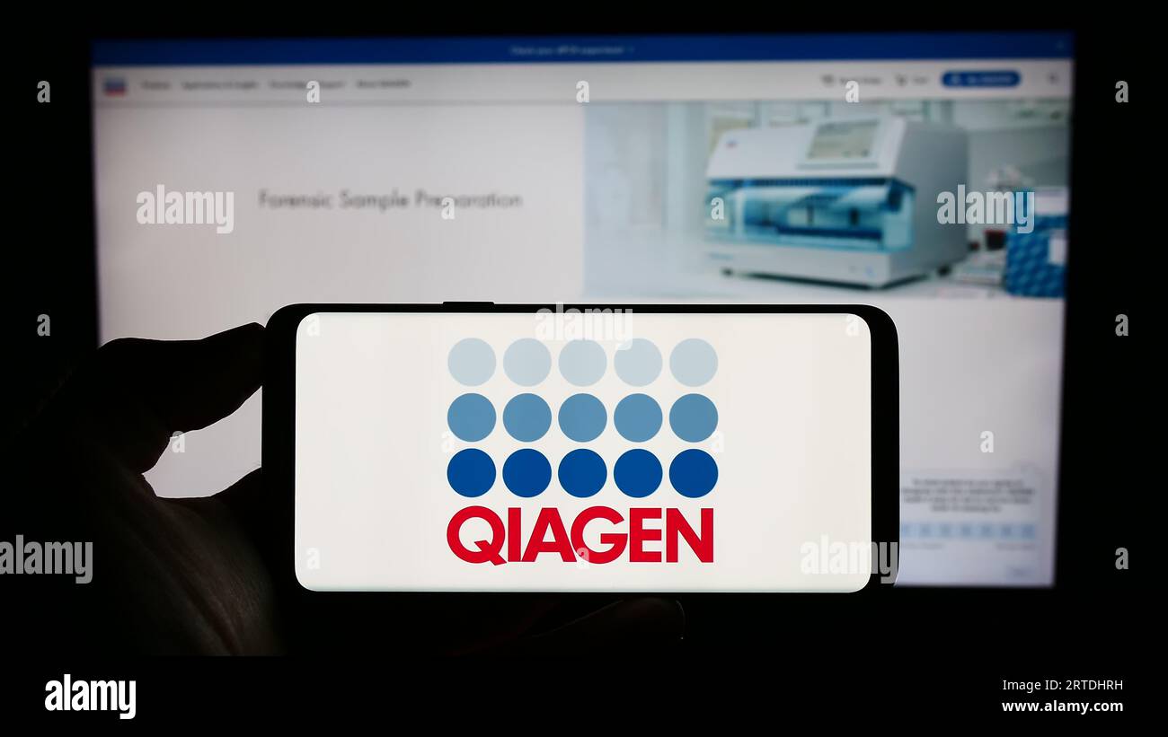 Personne tenant le téléphone portable avec le logo de la société de biotechnologie Qiagen N.V. sur l'écran devant la page Web de l'entreprise. Concentrez-vous sur l'affichage du téléphone. Banque D'Images