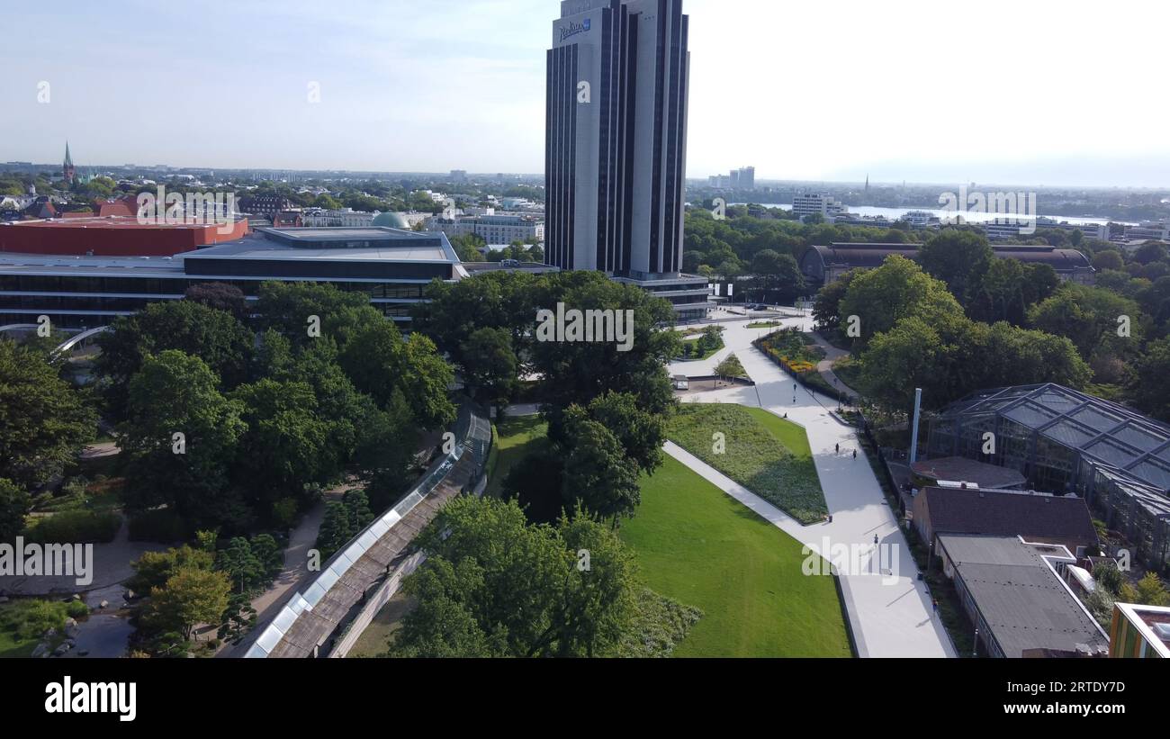 Jardin botanique : Planten un blomen à Hambourg et gratte-ciel (peut-être hôtel) et lac Aussen-Alster à distance - paysage urbain dans la matinée d'été Banque D'Images