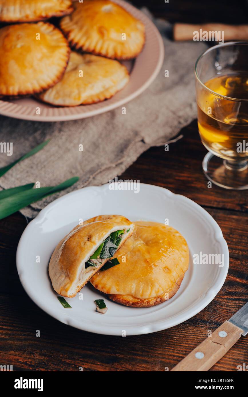 Pâtisseries cuites au four garnies de ciboulette bleue et de champignons sur assiette blanche et verre de vin Banque D'Images