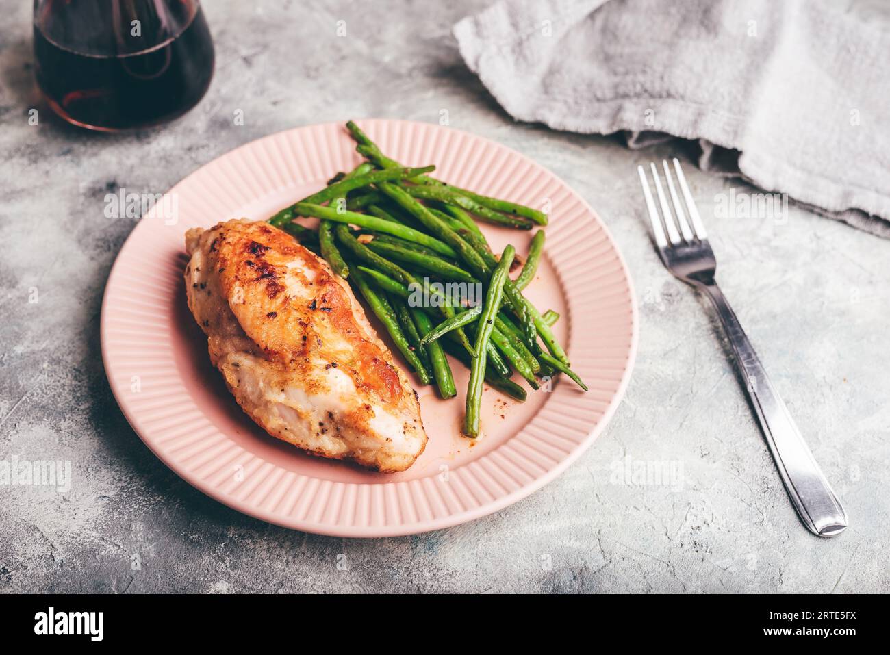 Poitrine de poulet croustillante cuite au four servie sur une assiette avec des haricots verts Frits avec de l'ail et du thym Banque D'Images