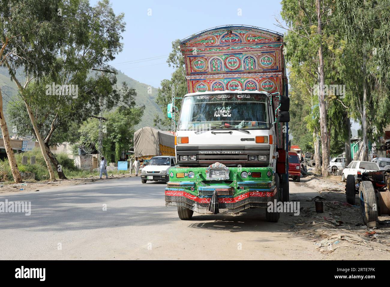 Camion peint traditionnel garé devant un atelier au Pakistan Banque D'Images