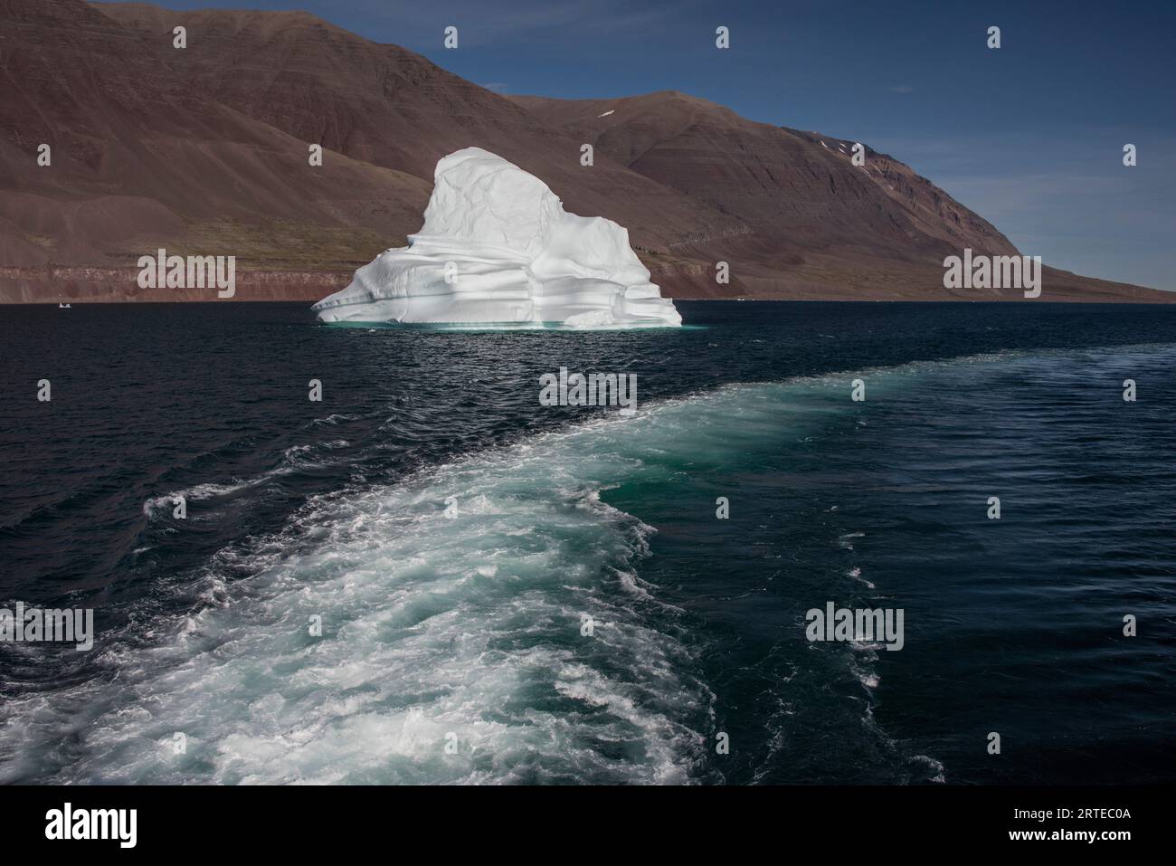 Le bateau se réveille à côté d'un petit iceberg flottant dans le fjord Kaiser Franz Joseph du Groenland ; est du Groenland, Groenland Banque D'Images