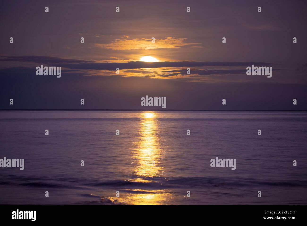 Lumière dorée réfléchie sur l'océan Pacifique avec la pleine lune couchant au Kamaole Beach Park ; Kihei, Maui, Hawaii, États-Unis d'Amérique Banque D'Images