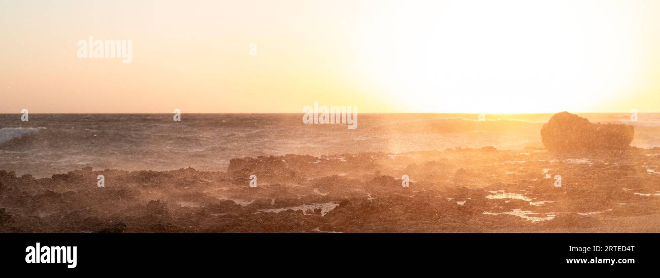 Une photo anti-lumière de minuscules gouttelettes de vagues de mer heurtant un brise-lames au coucher du soleil. Banque D'Images