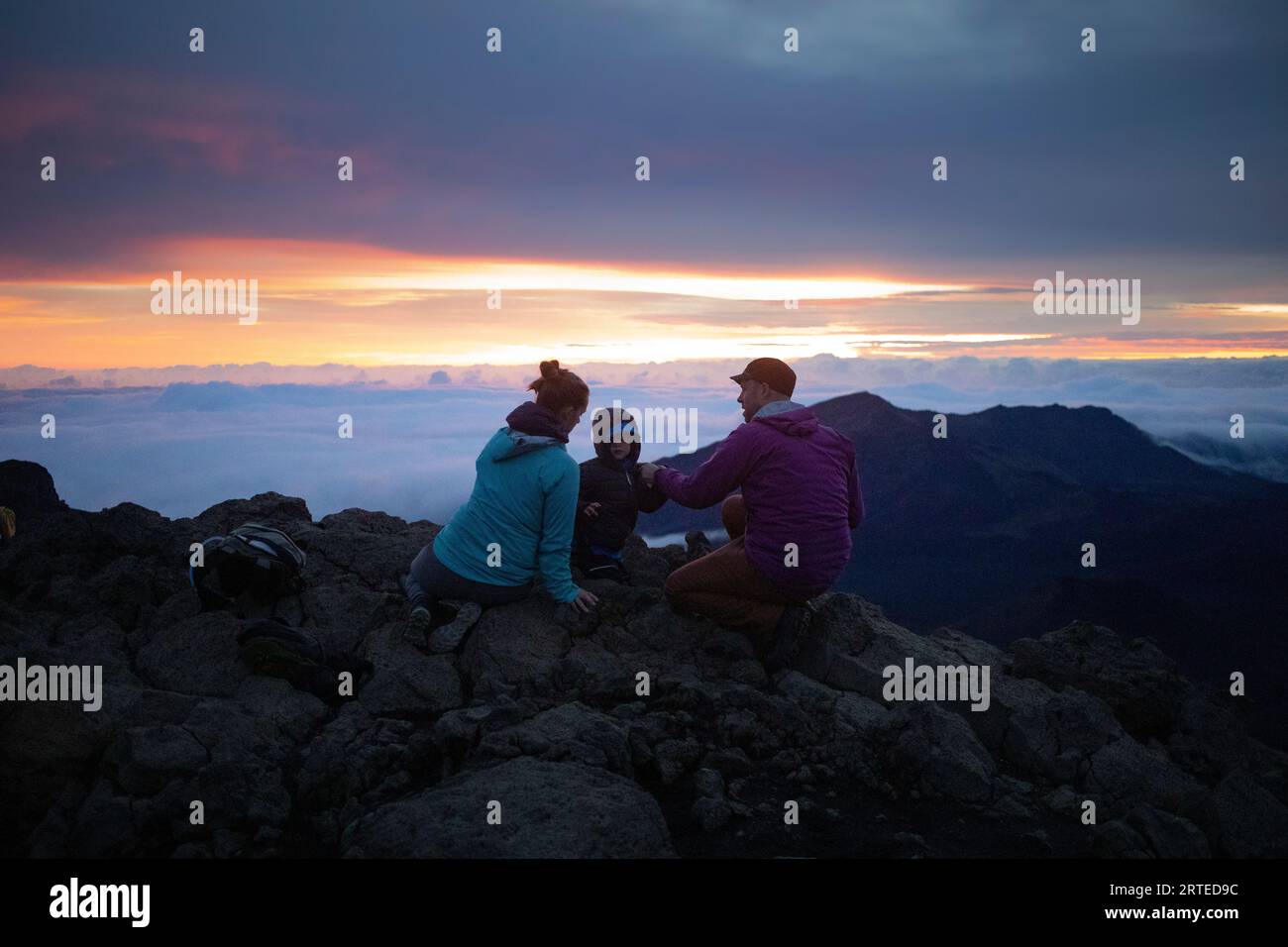 Famille sur un sommet de montagne au-dessus des nuages à Haleakala regarder le lever du soleil sur la côte Pacifique Banque D'Images