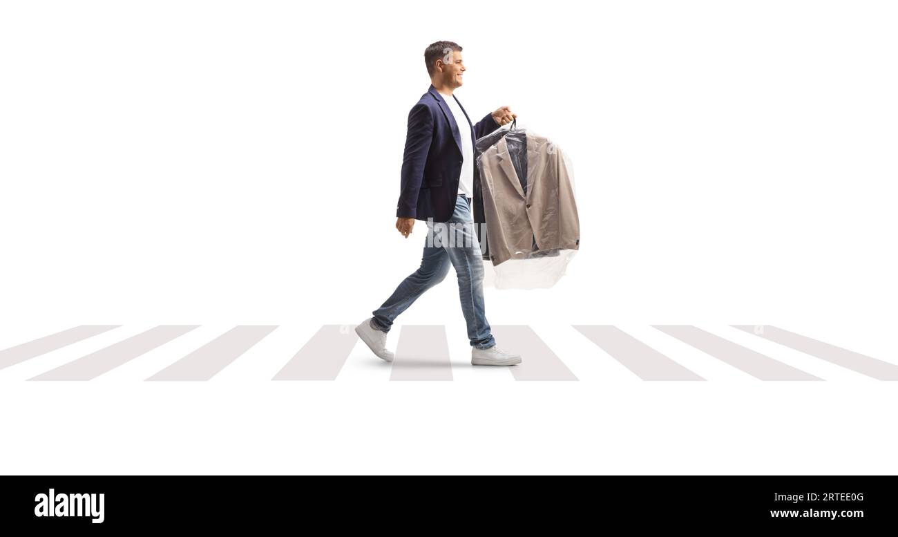 Homme portant une combinaison avec un sac de nettoyage à sec en plastique et traversant une rue isolée sur un fond blanc Banque D'Images