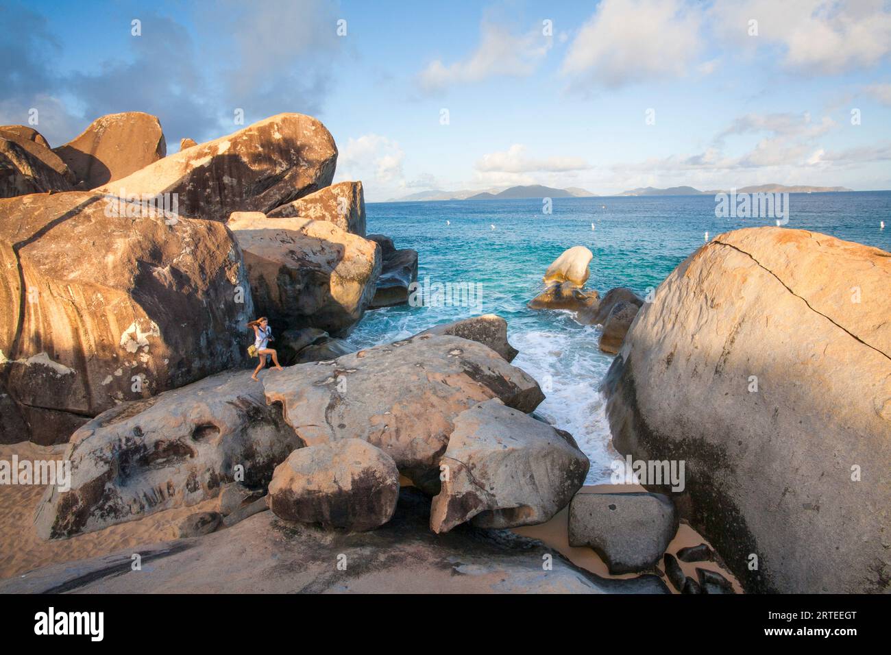 Vue panoramique d'une femme marchant sur les grands rochers sur les rives du bord de mer des thermes au crépuscule, une célèbre plage dans les BVI Banque D'Images