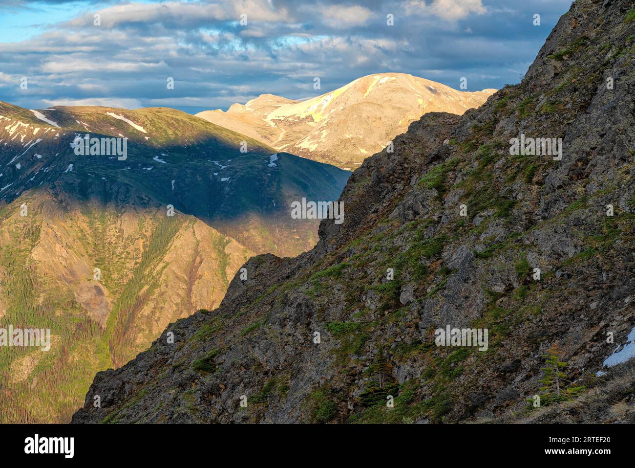Vue rapprochée des sommets de montagne qui commencent à être peints de couleur par la lumière chaude du coucher du soleil ; Carcross, territoire du Yukon, Canada Banque D'Images
