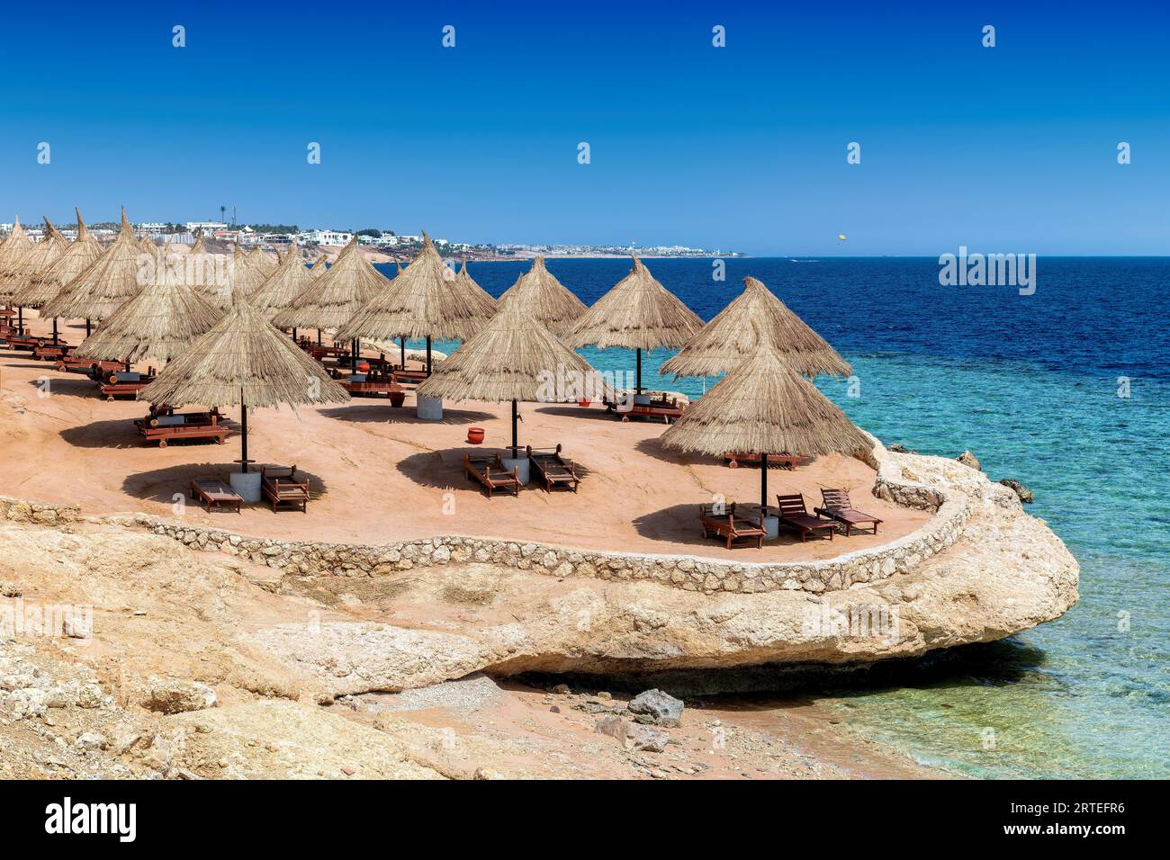 Station balnéaire ensoleillée de corail tropical avec parasols de paille à Charm el Cheikh, Egypte. Banque D'Images