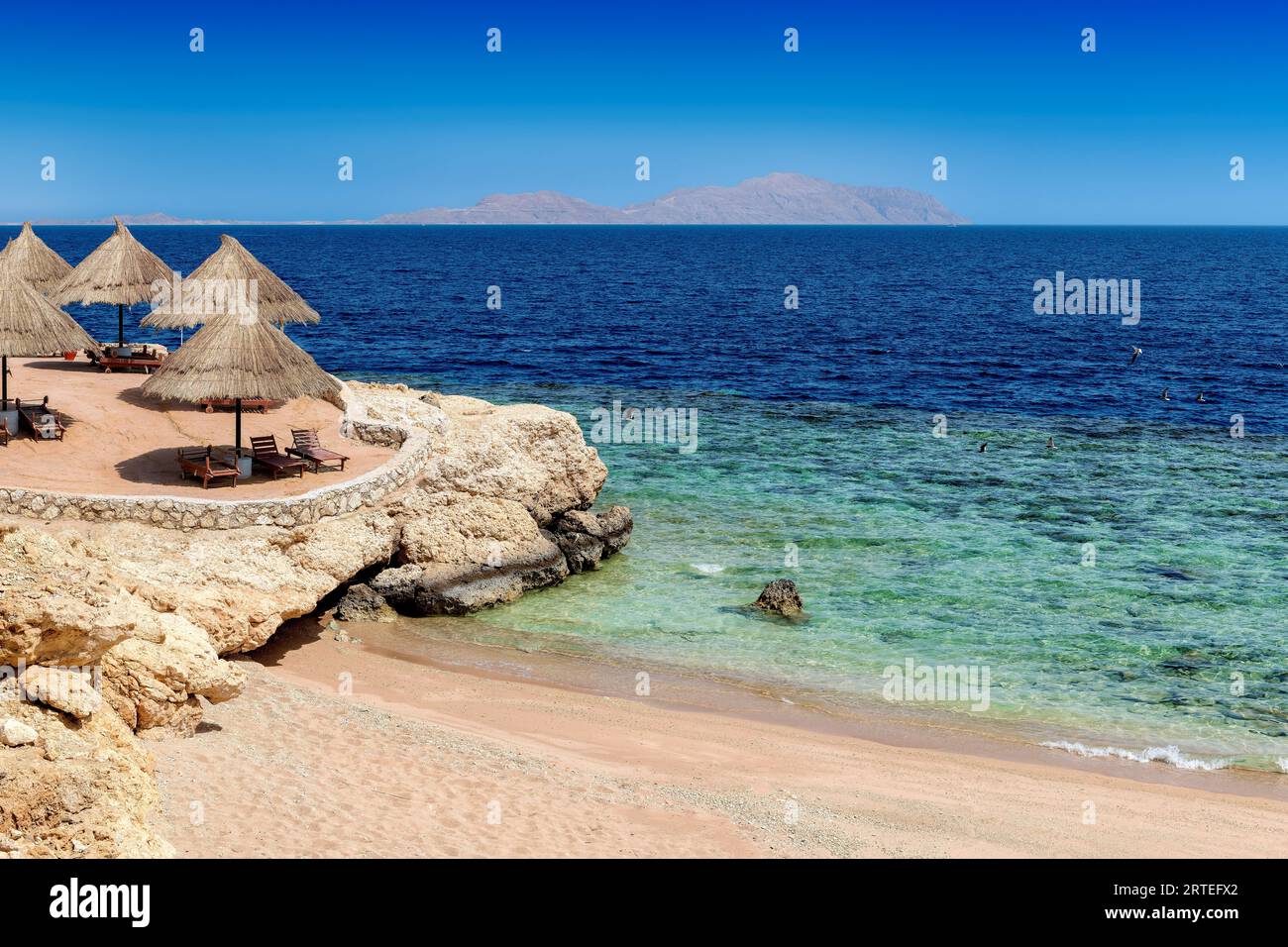 Station balnéaire ensoleillée de corail tropical avec parasols de paille à Charm el Cheikh, Egypte. Banque D'Images