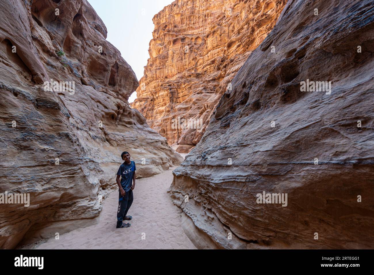 Jeune garçon bédouin dans un étroit canyon rocheux dans le désert de Wadi Rum, Jordanie Banque D'Images