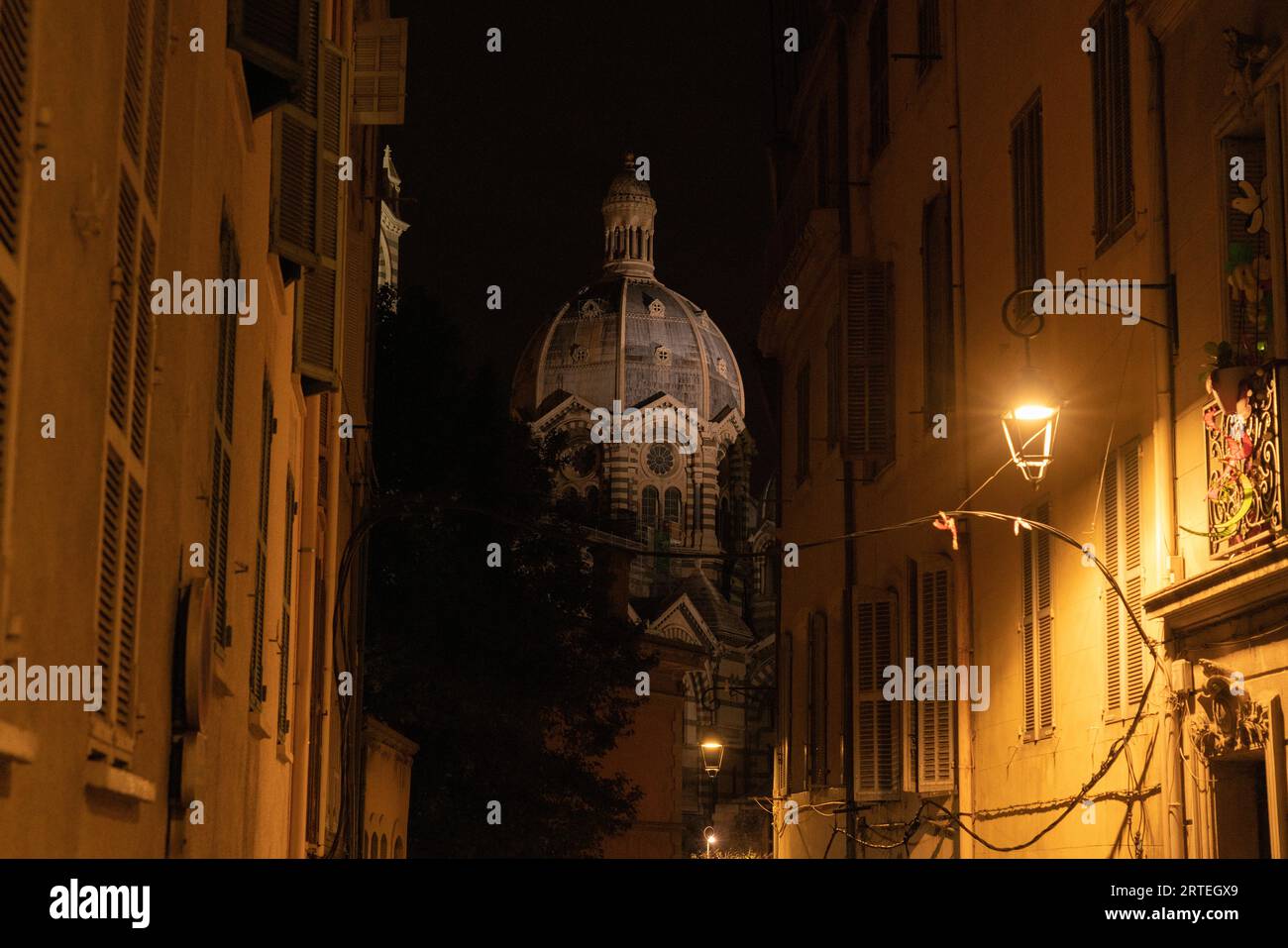 Grand dôme de la cathédrale de Marseille la nuit vue entre les bâtiments illuminés par une lumière ; Marseille, France Banque D'Images