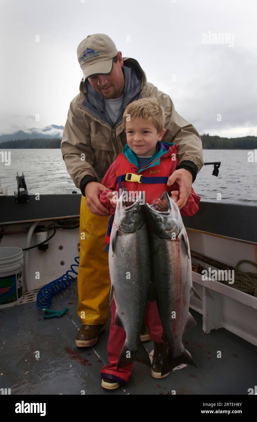 Homme et garçon avec du saumon argenté pêché (Oncorhynchus kisutch) dans la baie Thorne ; Alaska, États-Unis d'Amérique Banque D'Images