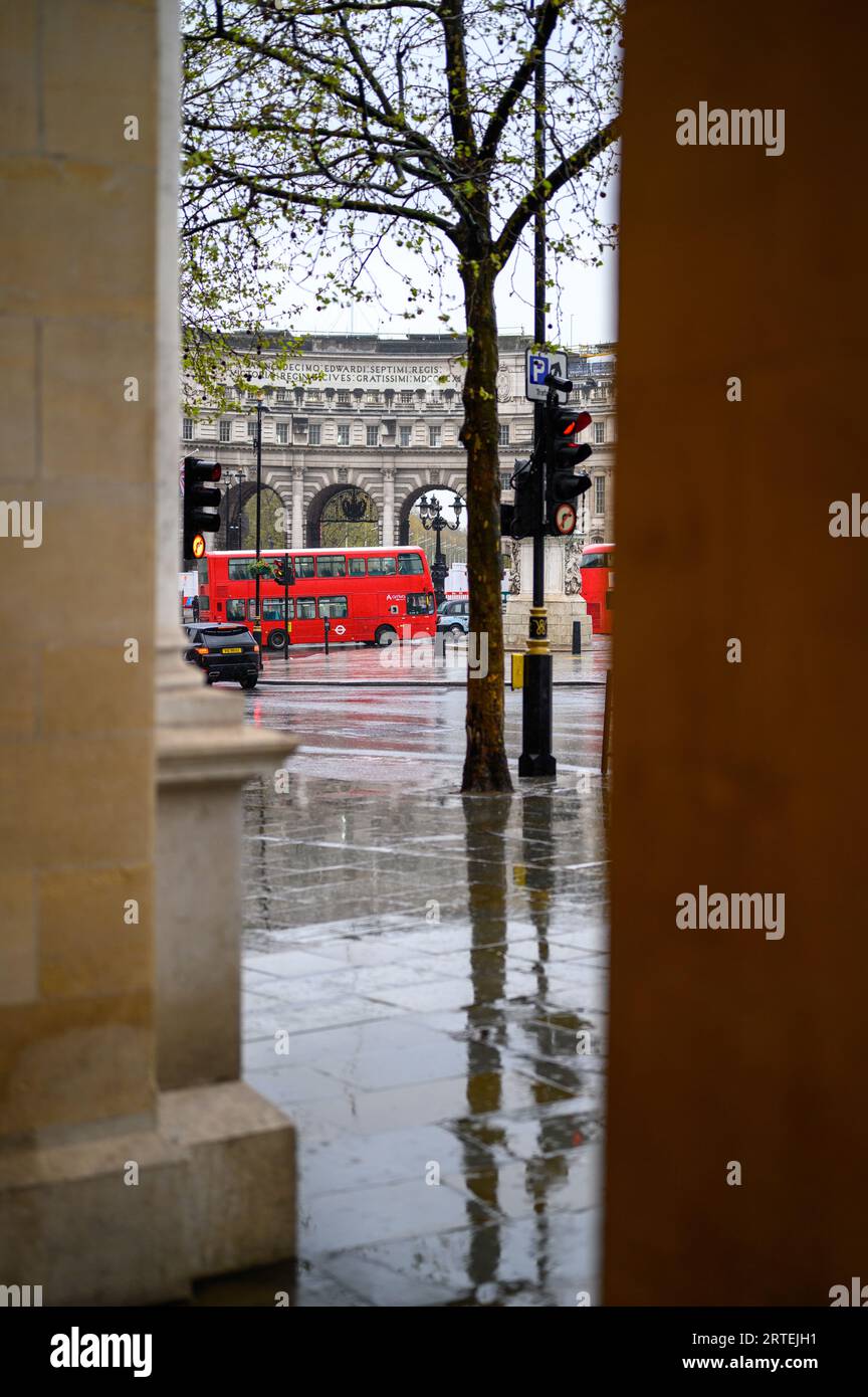 LONDRES - 24 avril 2023 : l'emblématique bus rouge londonien ajoute de la vitalité à une toile de fond pluvieuse à Admiralty Arch. Banque D'Images