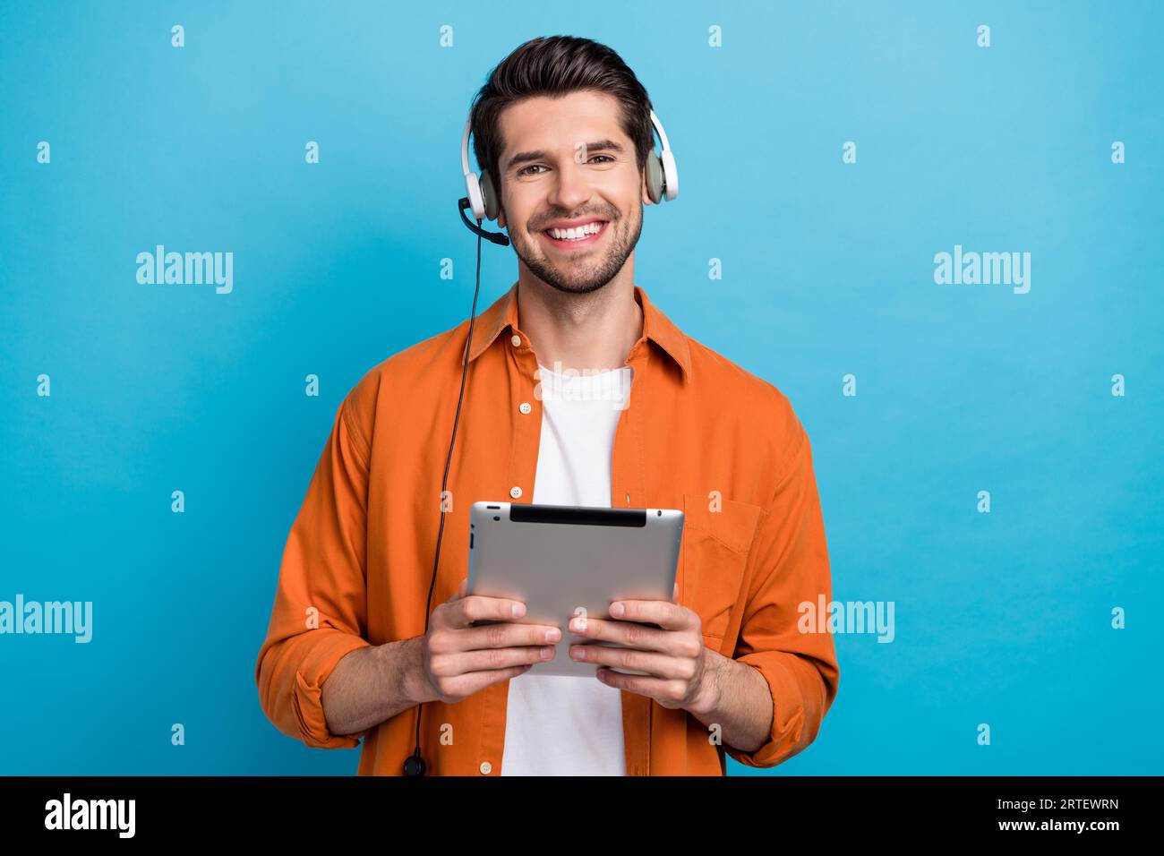 Portrait d'un beau gars positif souriant tenir le sourire utilisez le casque filaire de la tablette communiquer les clients isolés sur fond bleu Banque D'Images