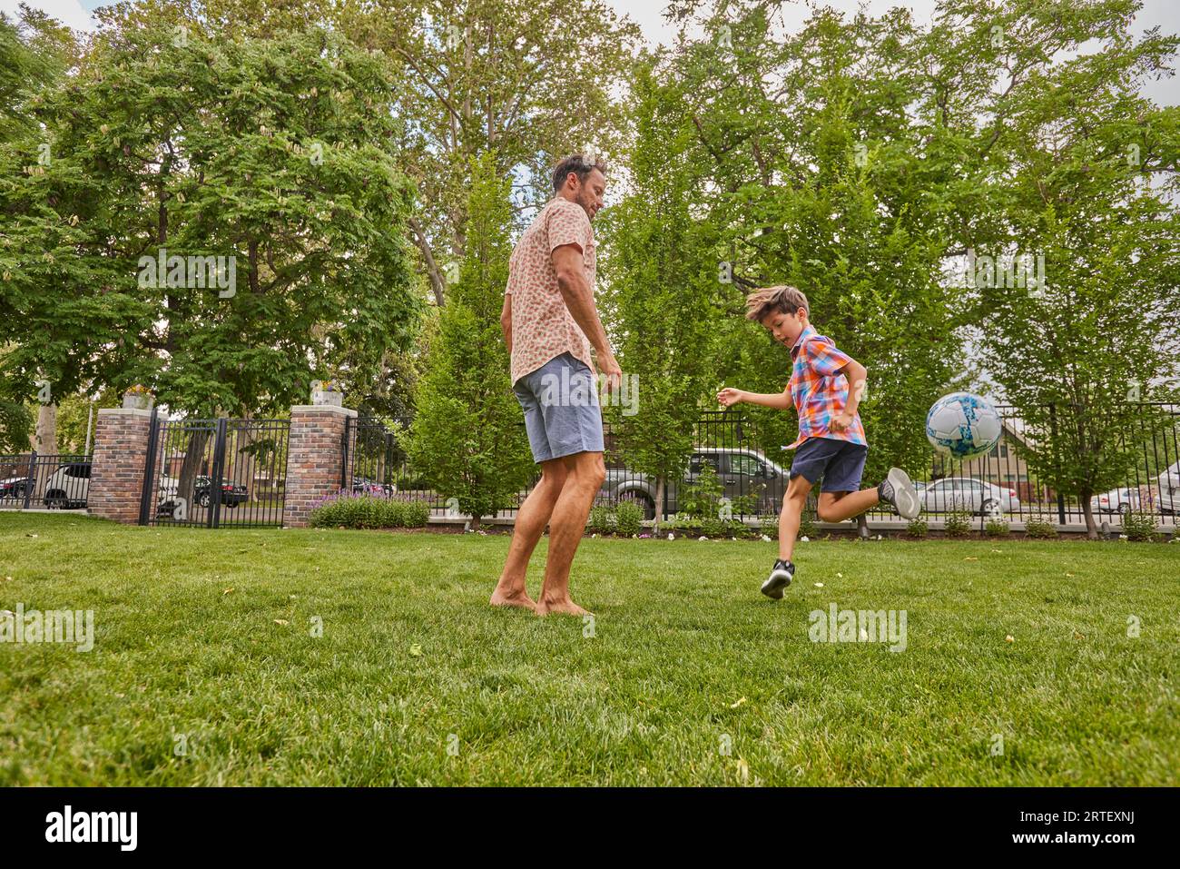 Père et fils (8-9) jouant au soccer dans le parc Banque D'Images