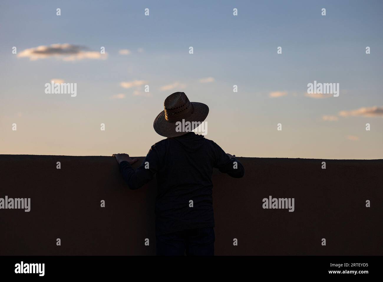 Silhouette en chapeau regardant le coucher du soleil Banque D'Images