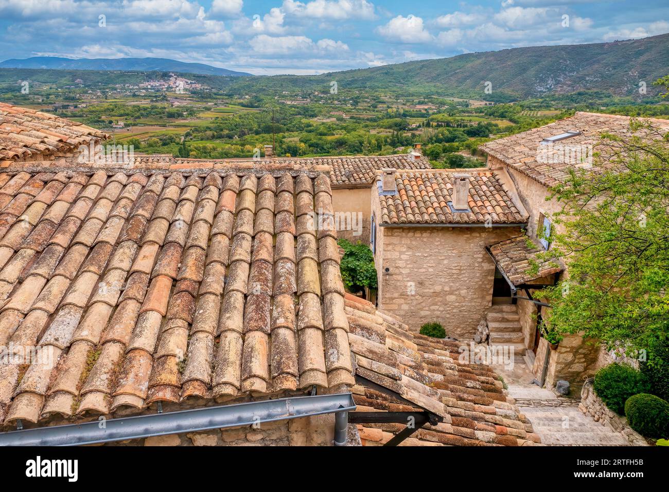 Dans le quartier historique de Lacoste, en Provence, les vieilles maisons traditionnelles en pierre aux toits de tuiles surplombent la campagne française luxuriante, avec le village de Bonnieux visibl Banque D'Images