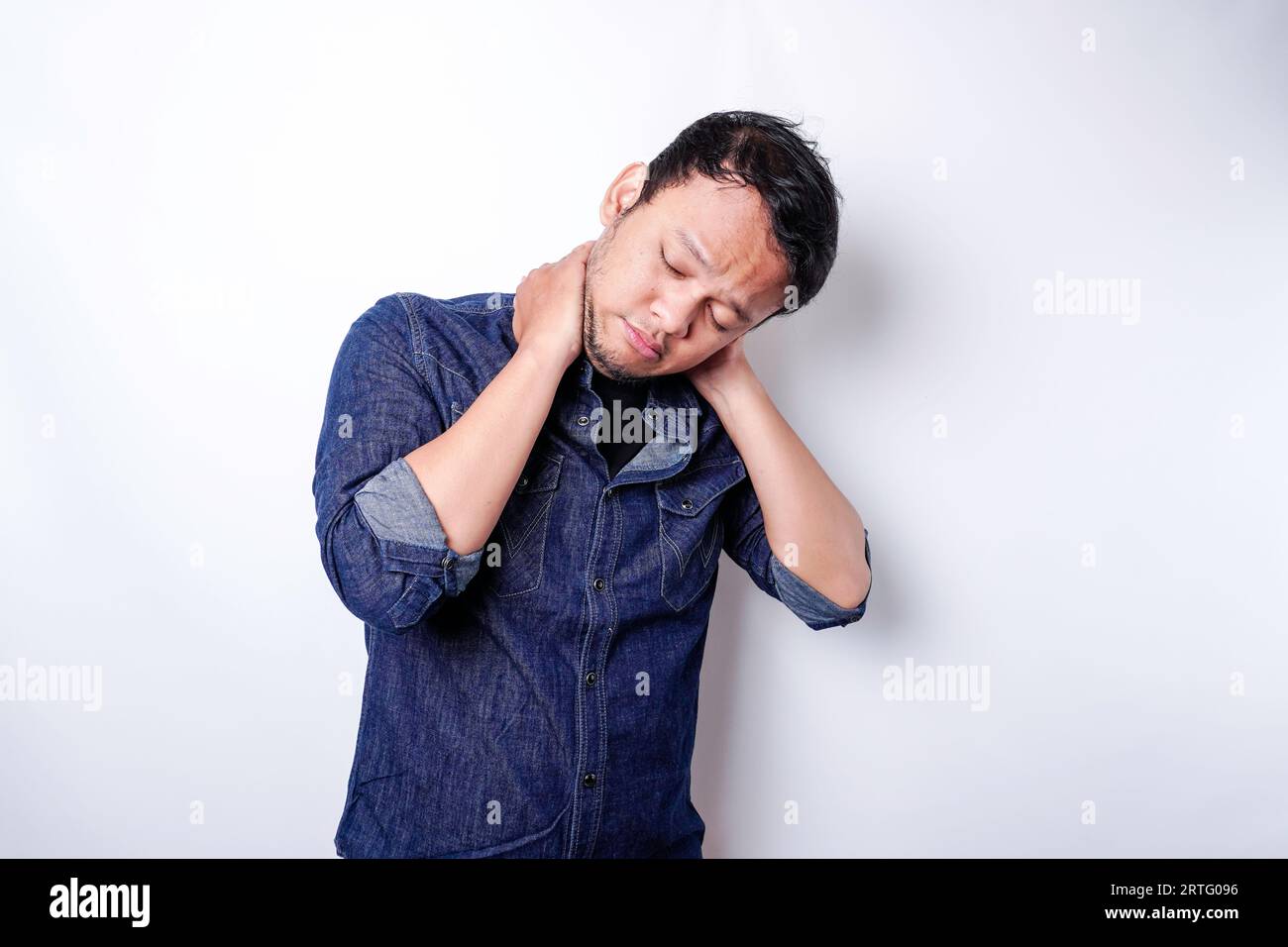 Fatigué bouleversé jeune homme porte une chemise bleue souffrant de douleurs, de spasmes musculaires au travail. Fatigue, délai, douleur et posture incorrecte Banque D'Images