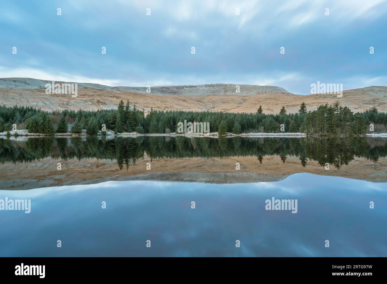 Montagnes et limite des arbres, reflétées dans les eaux calmes d'un lac de montagne. Brecon Beacons Banque D'Images