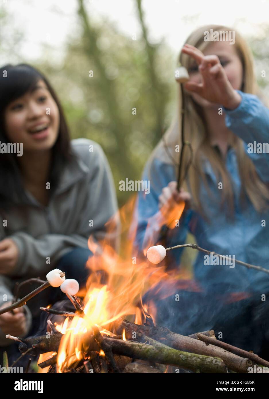 Deux adolescentes sourire guimauve rôtir sur un feu de camp Banque D'Images