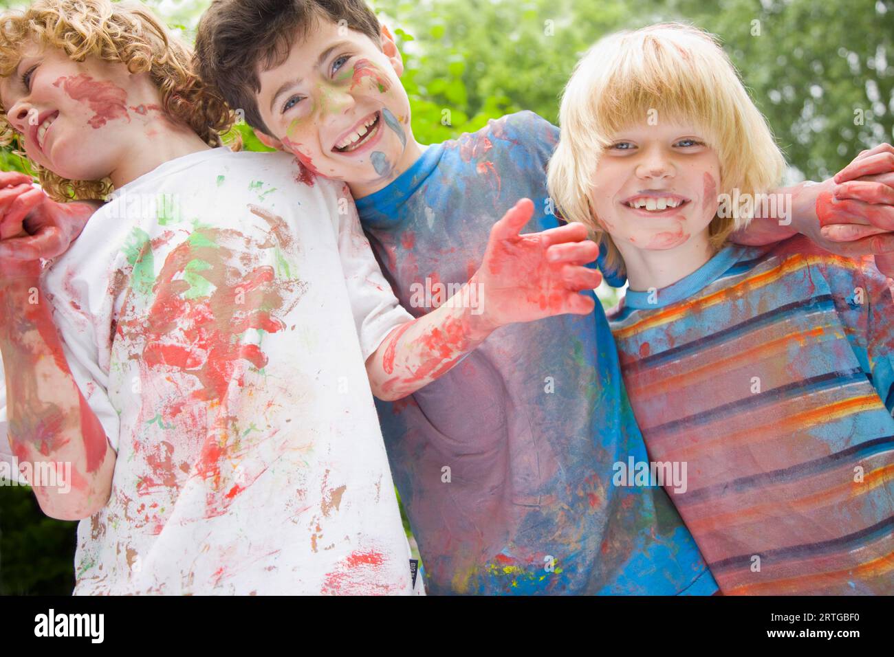 Jeunes garçons couverts de peinture aquarelle riant dans un jardin Banque D'Images