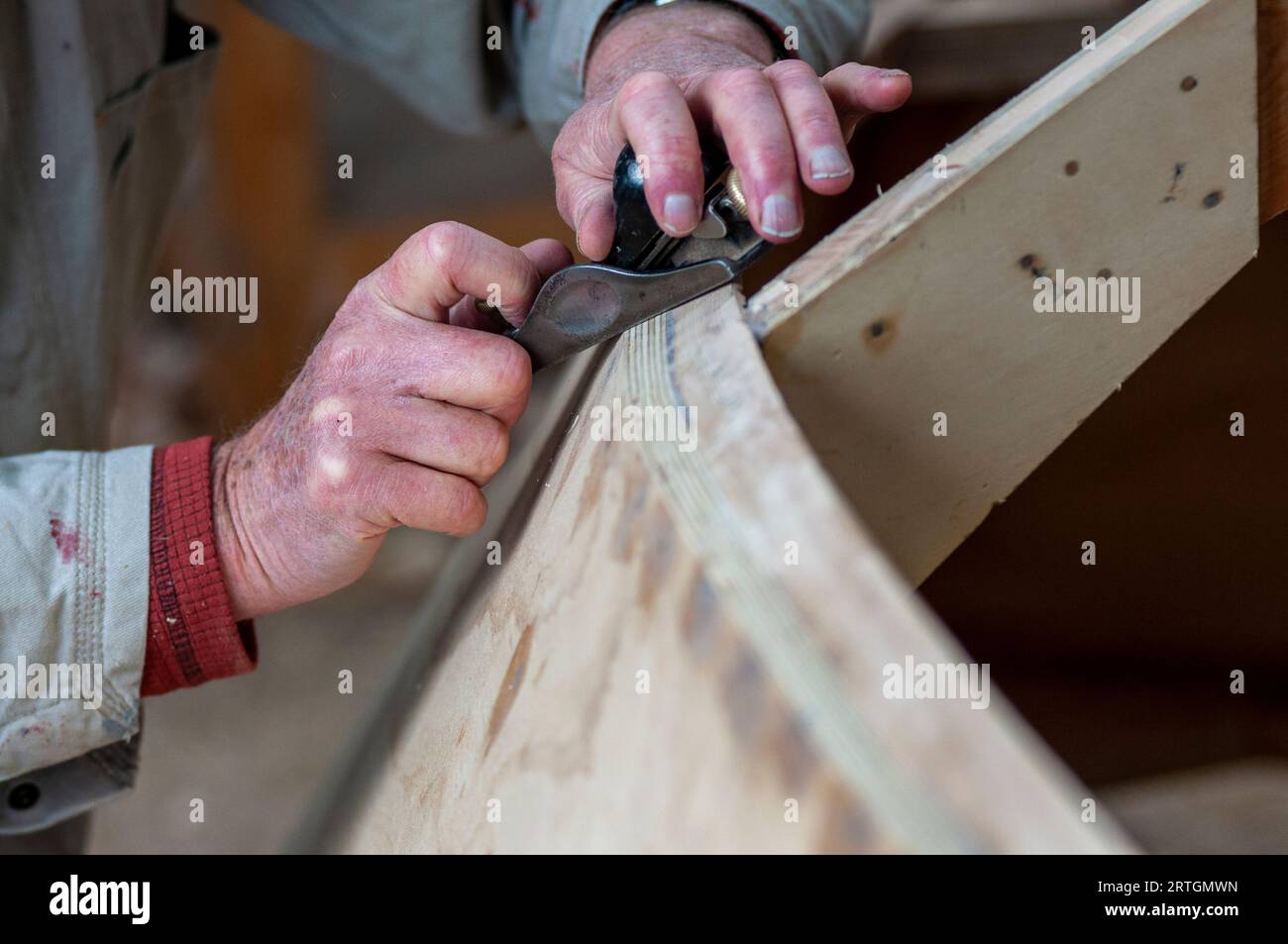 Mains d'un artisan constructeur de bateaux en bois utilisant un petit avion traditionnel Banque D'Images