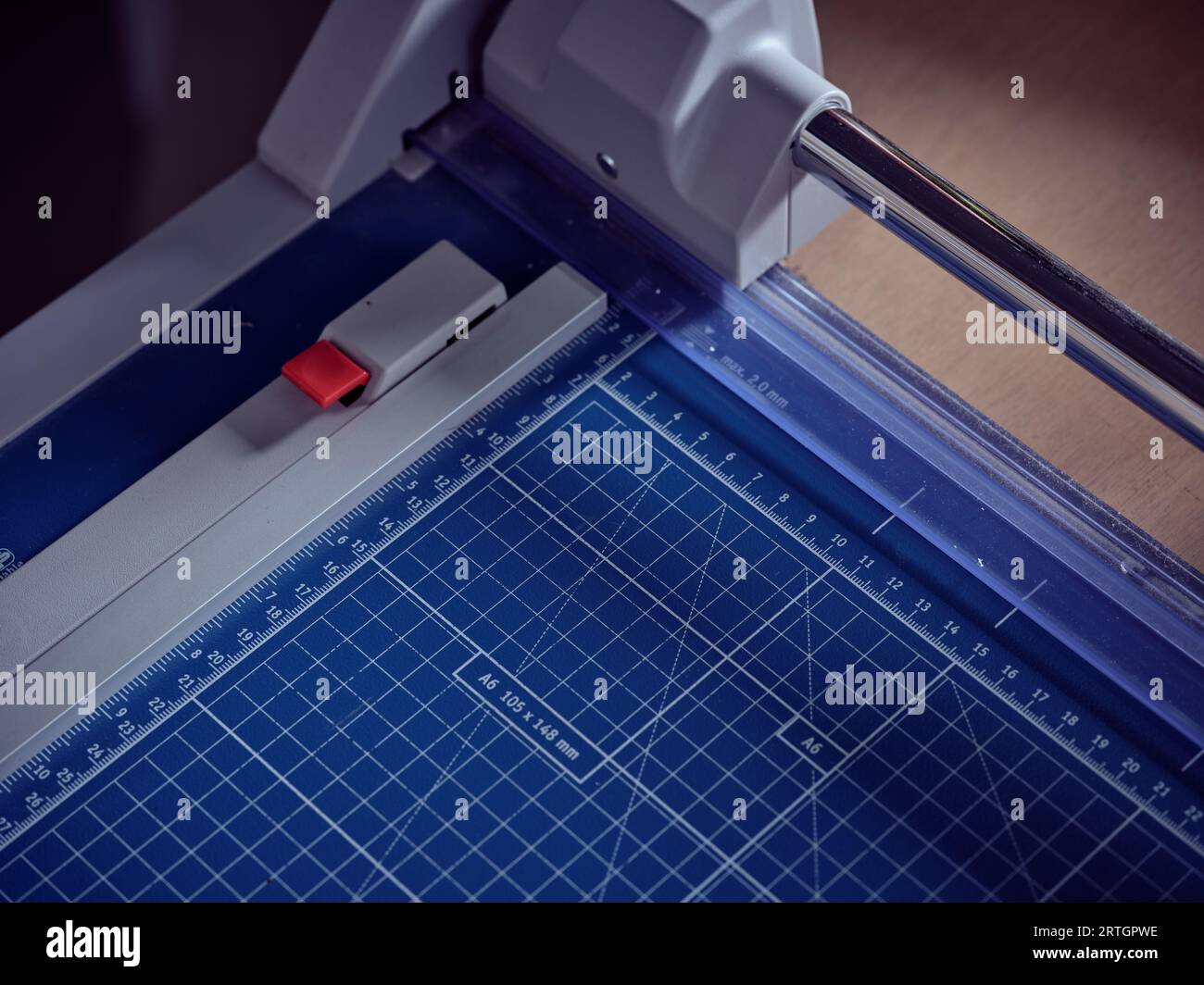 Gros plan à angle élevé de la machine de découpe moderne professionnelle avec papier millimétré bleu placé sur la table dans l'atelier de reliure Banque D'Images