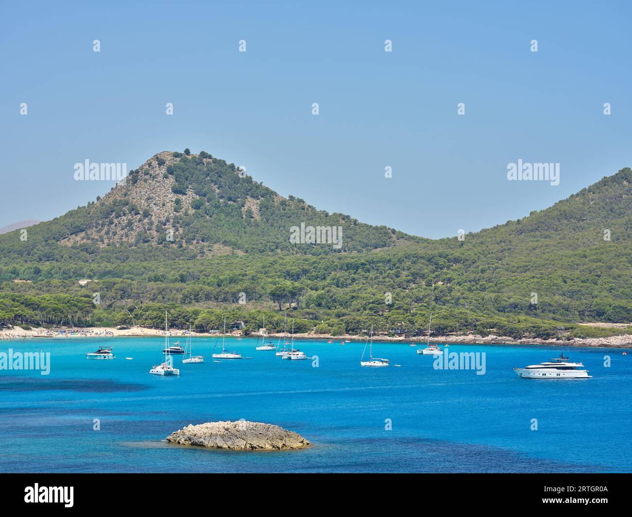 Yachts flottant dans l'eau de mer calme turquoise près de crête de montagne boisée sur une journée ensoleillée sous un ciel bleu sans nuages Banque D'Images