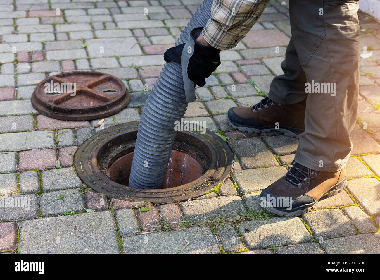 travailleur tenant le tuyau et pompant la fosse septique domestique. service de nettoyage des égouts et des eaux usées Banque D'Images