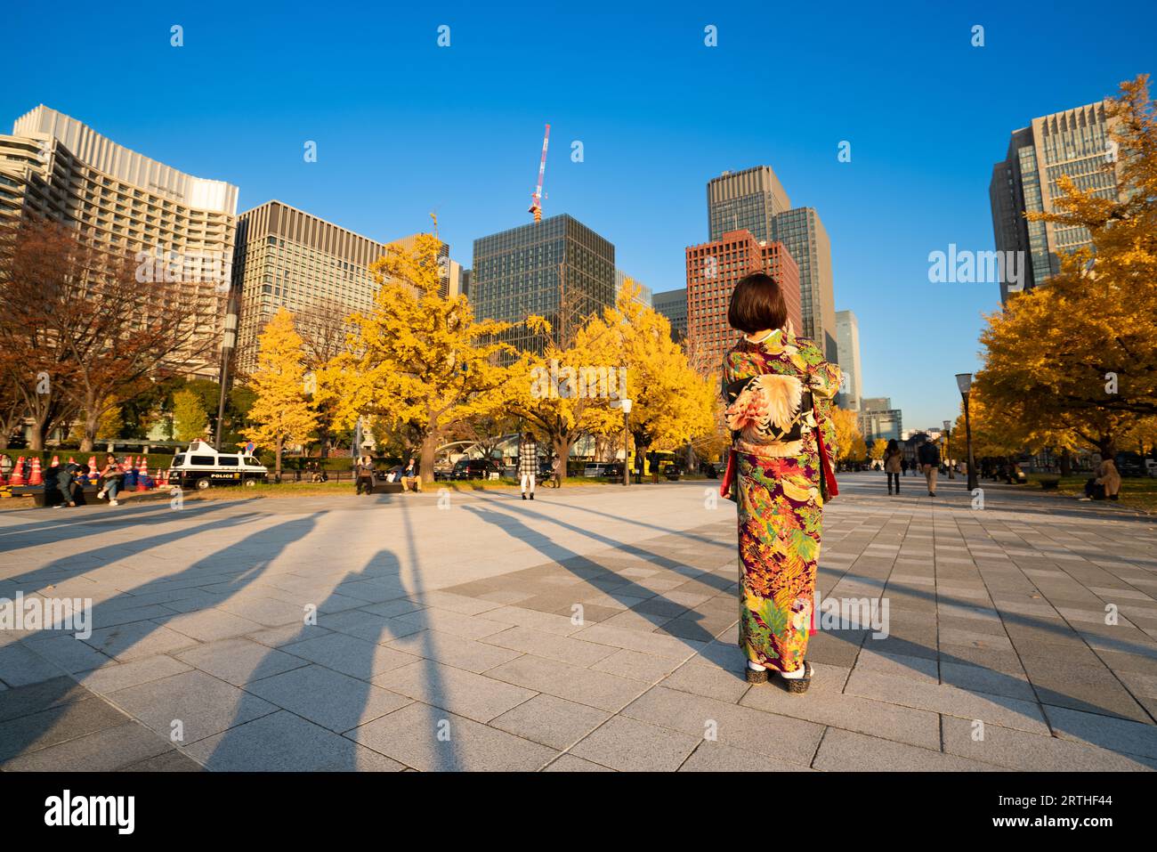 Une femme asiatique portant un kimono traditionnel japonais debout avec des feuilles de ginko ou du feuillage d'automne près de la gare de Tokyo, au Japon Banque D'Images