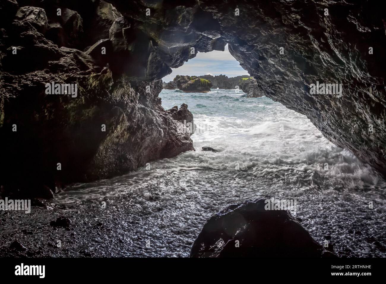 Le surf se jette dans une grotte à Waianapanapa Black Sand Beach près de Hana sur Maui, Hawaii, États-Unis Banque D'Images