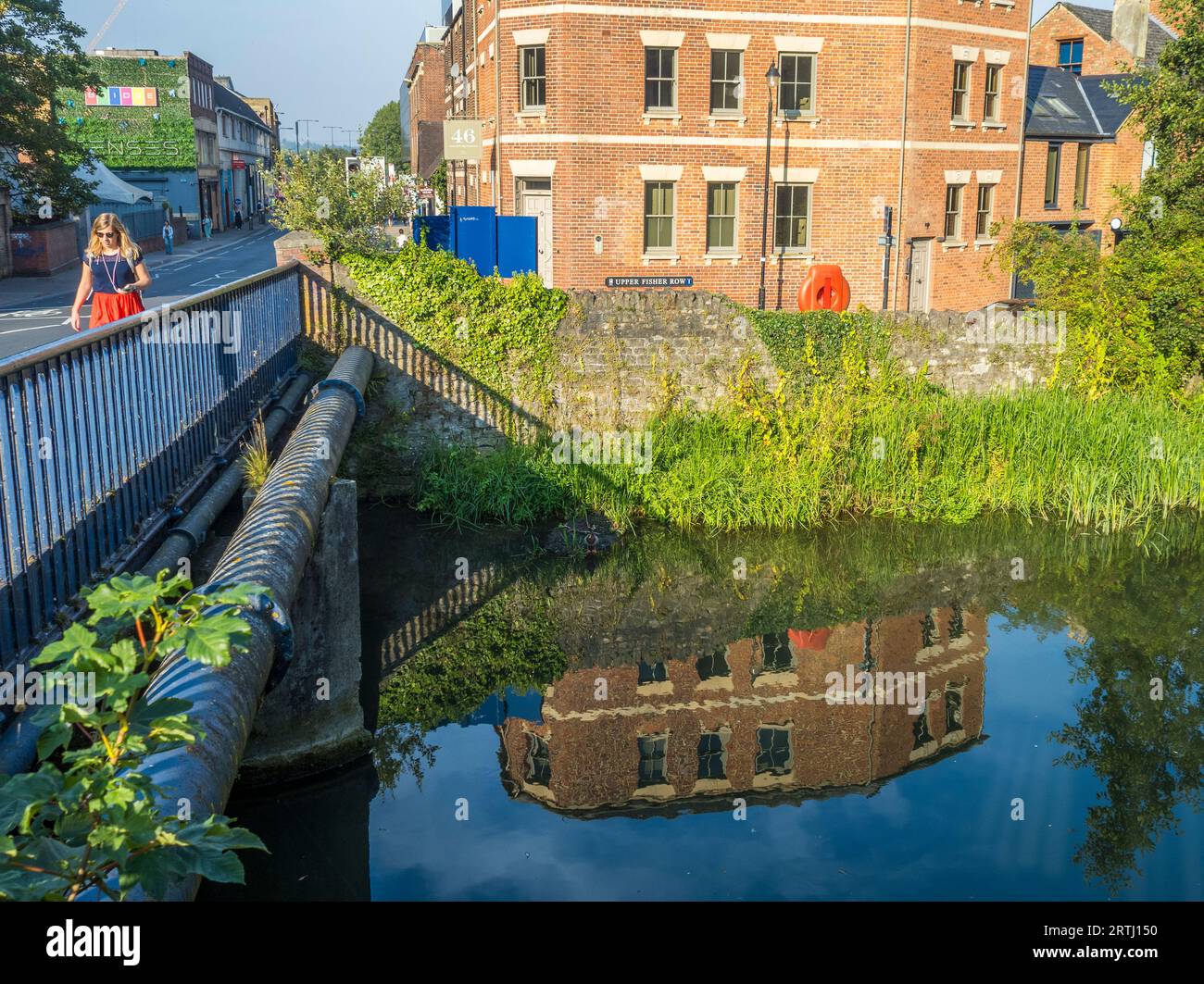 Femme marchant à travers Hythe Bridge, Castle Mill Stream, Oxford, Oxfordshire, Angleterre, ROYAUME-UNI, GB. Banque D'Images