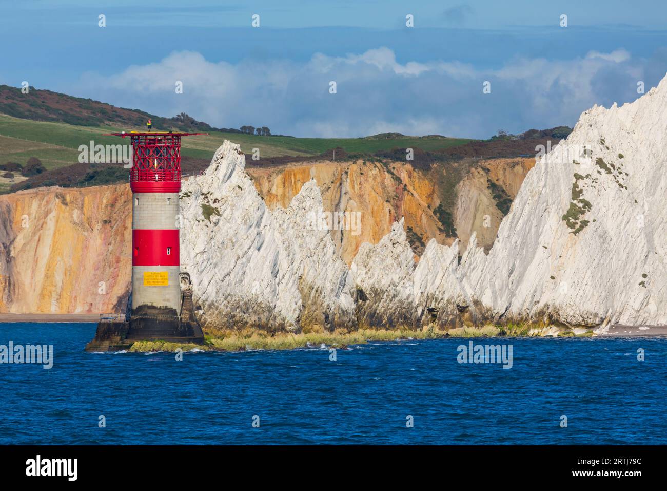 Le soleil du soir illumine le phare et les pierres empilées d'aiguilles à l'île de Wight, Hampshire Royaume-Uni en septembre Banque D'Images