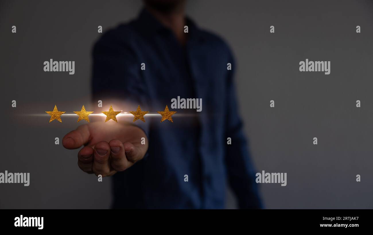 Concept de satisfaction et de service à la clientèle. Homme d'affaires tenant l'écran virtuel les cinq étoiles pour montrer la satisfaction ou le service ou donner le taux. Banque D'Images