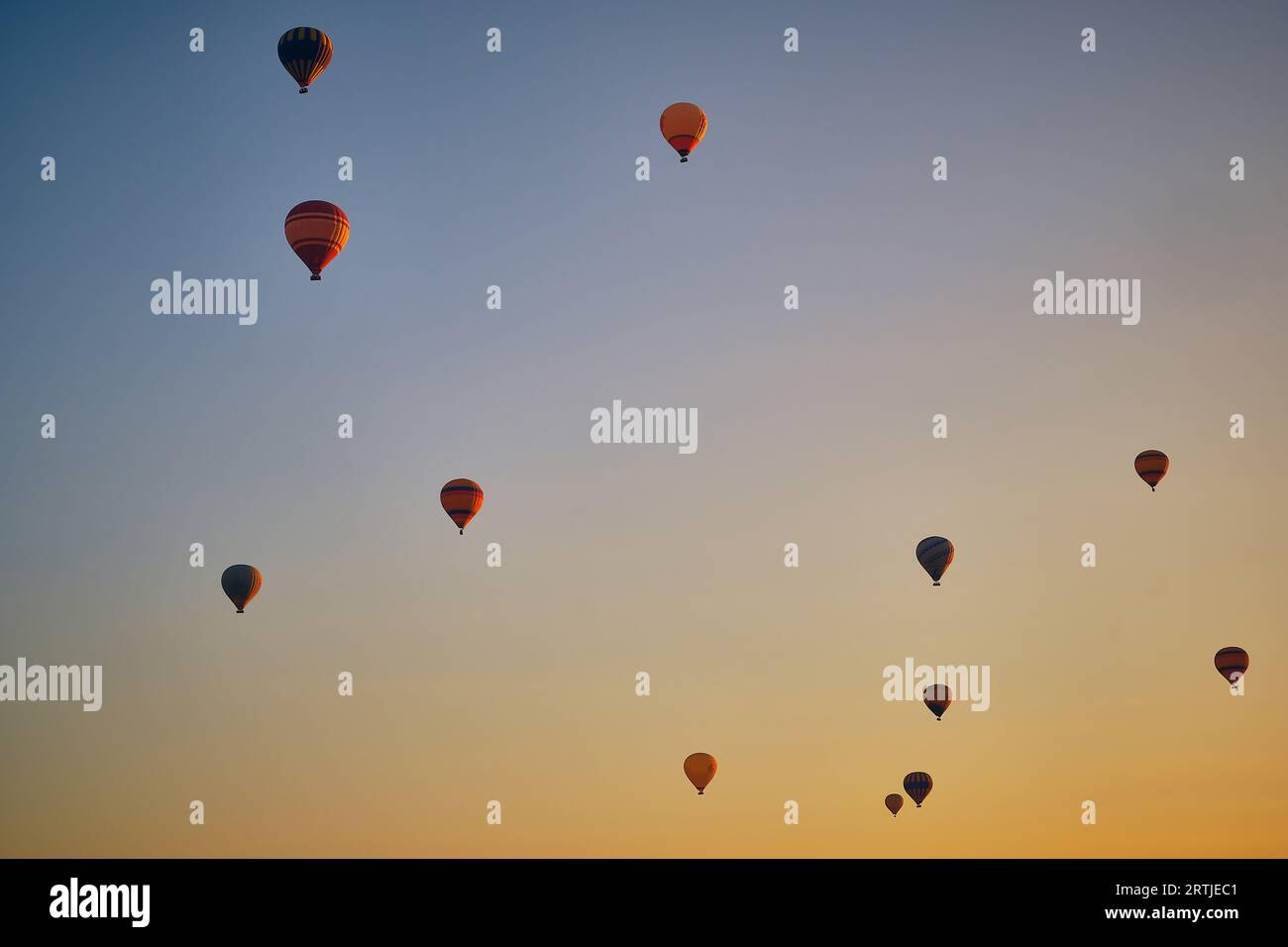 Vol de montgolfières contre le ciel d'aube bleu et jaune brillant Banque D'Images