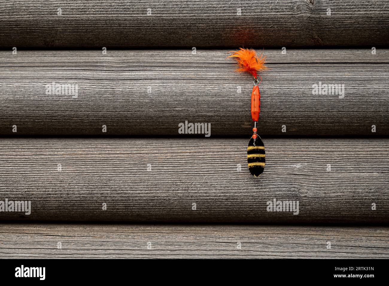 leurre de pêche rouge accroché sur un mur en bois gris Banque D'Images