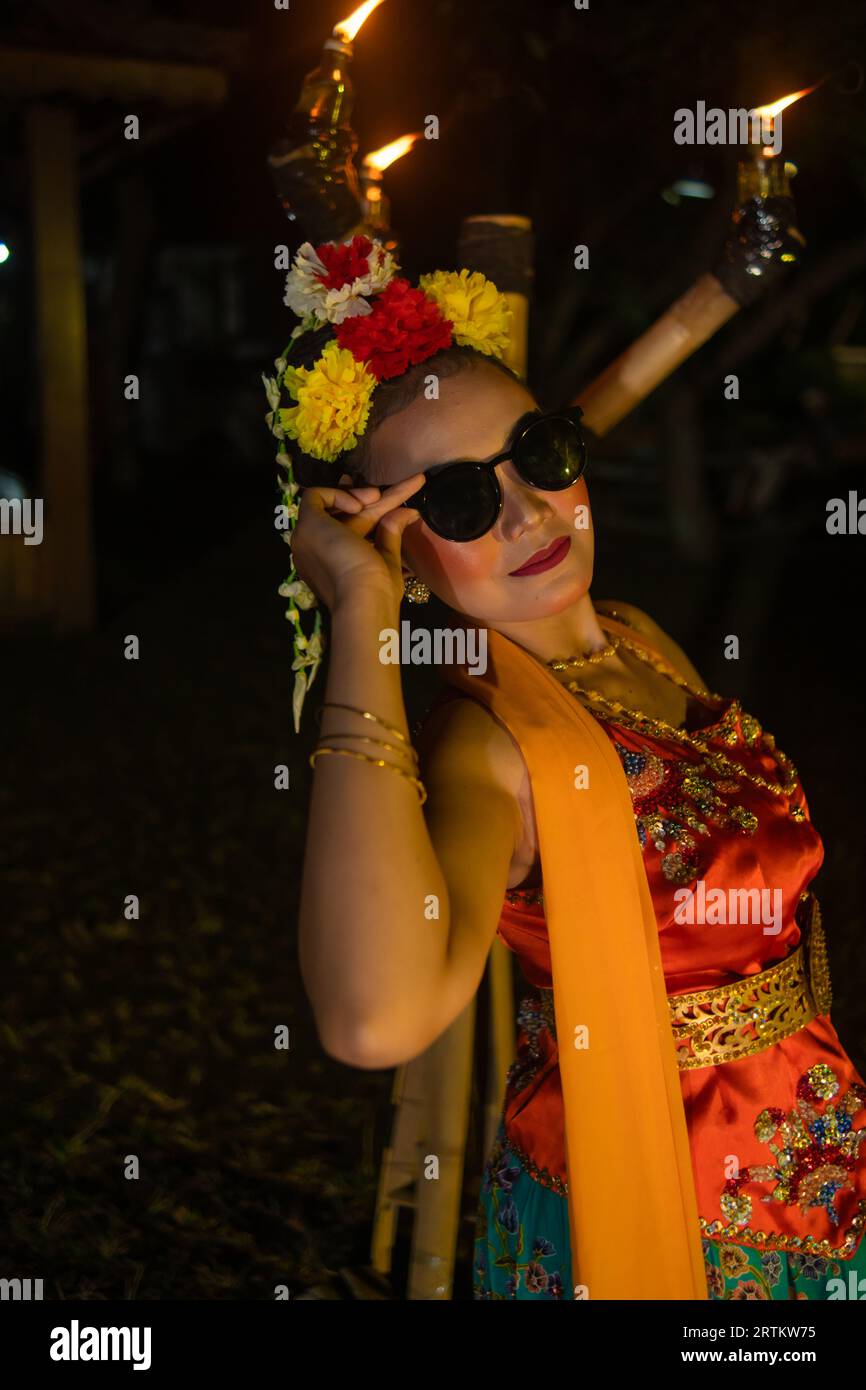 une danseuse asiatique traditionnelle pose avec des lunettes de soleil tout en dansant sur scène la nuit Banque D'Images